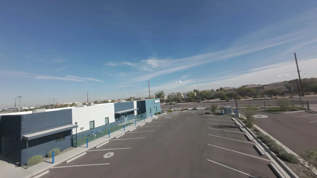 Commercial building with a flat roof and parking lot, seen from a drone
