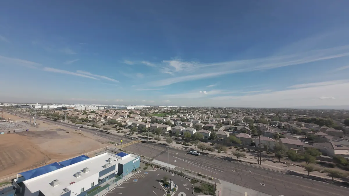Drone view of a commercial building with a white flat roof beside a Phoenix-area neighborhood