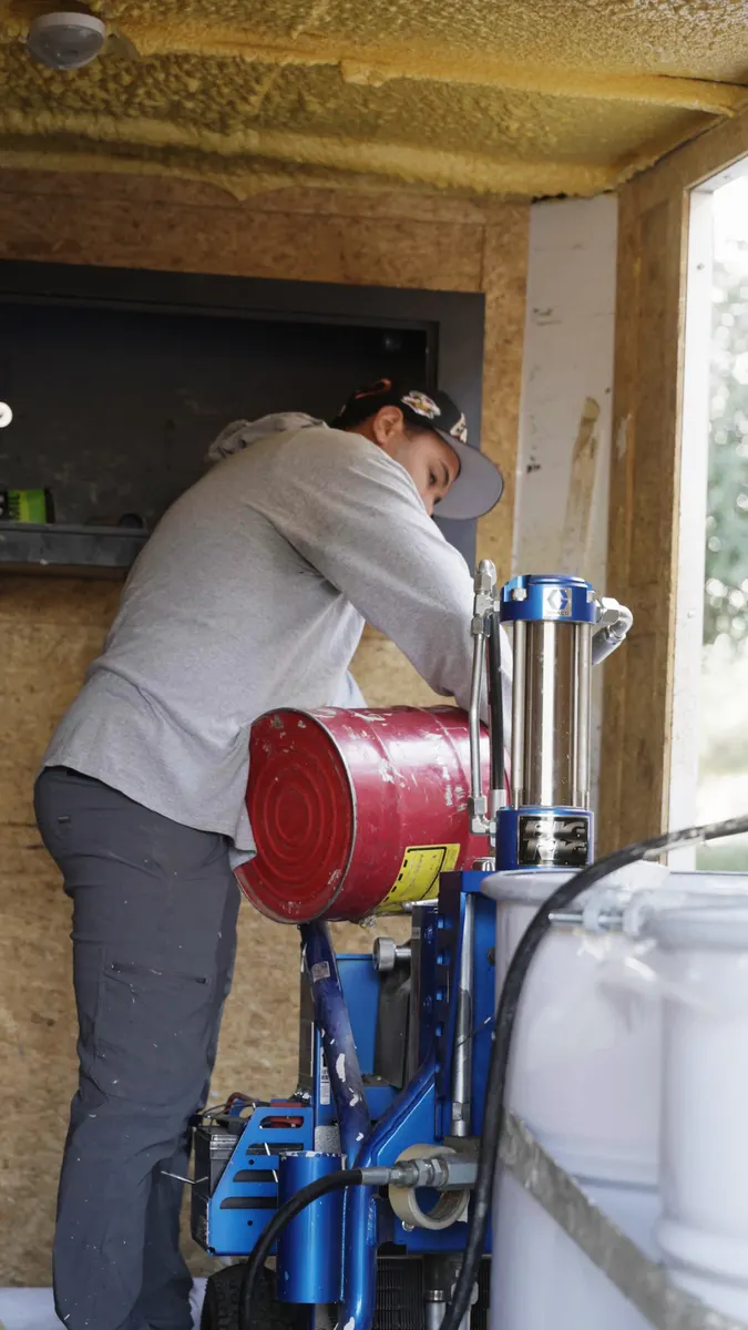 Simply Roofing crew member setting up a spray rig inside an equipment trailer