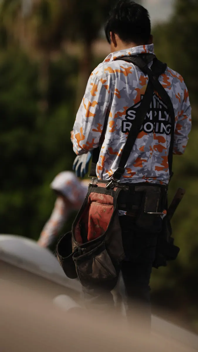 Roofer wearing a Simply Roofing work shirt and tool belt on the job